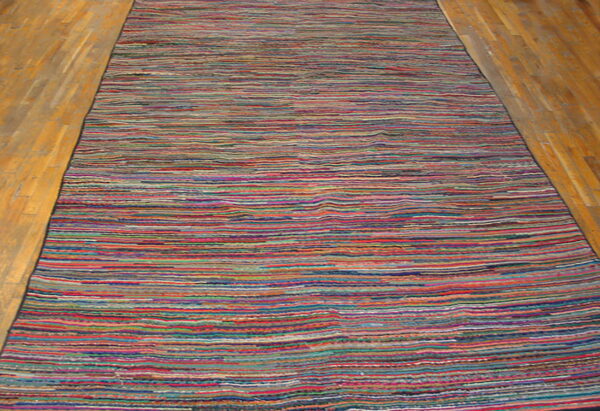 A multicolored striped runner rug lies on light brown hardwood flooring.