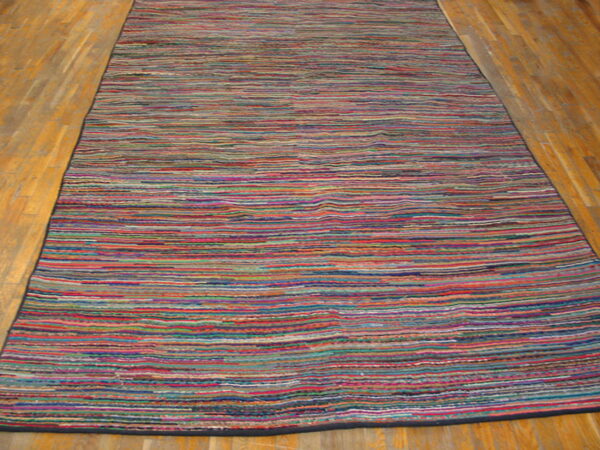 A long runner rug displaying tight multicolored horizontal stripes rests on light wooden plank flooring.