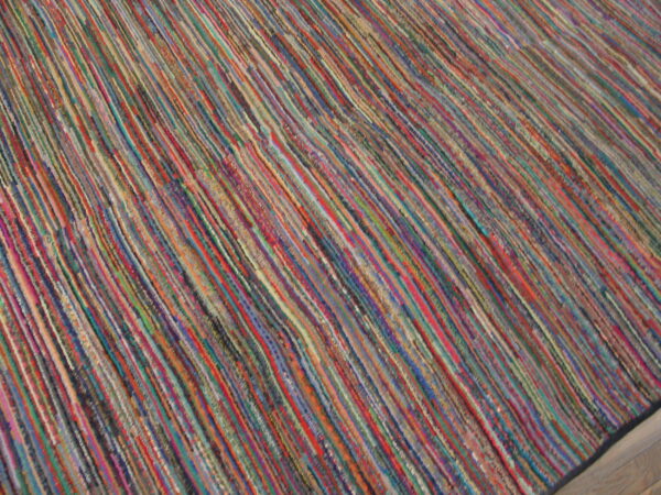 Textured multicolor rug with narrow diagonal stripes resting on a light wooden floor.