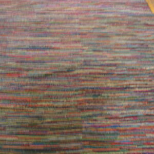 Multicolored rug with blurred horizontal stripes in red, blue, and green, flanked by golden wood floor.