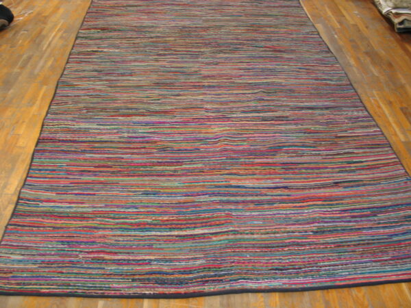 A long, multicolored striped runner rug with visible texture lies on a glossy wood floor.