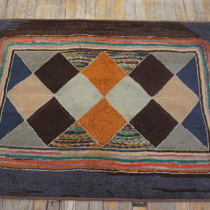 High-pile rug with geometric orange, brown, and gray diamonds, multicolored stripes, resting on distressed wood floor.