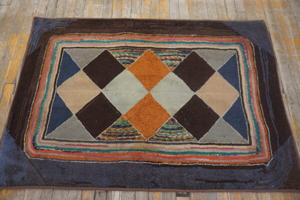 High-pile rug with geometric orange, brown, and gray diamonds, multicolored stripes, resting on distressed wood floor.