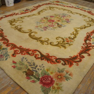 Low pile cream rug featuring a large multicolored floral medallion and ornate scrolling borders over distressed wood planks.