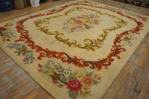 Low pile cream rug featuring a large multicolored floral medallion and ornate scrolling borders over distressed wood planks.