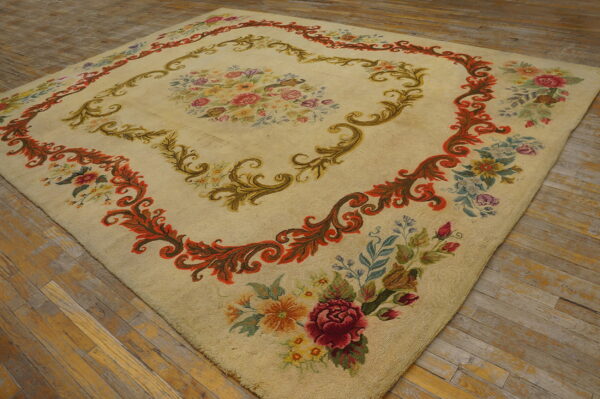 Cream rug with a colorful floral center and intricate rust and green scrolling borders on plank flooring.