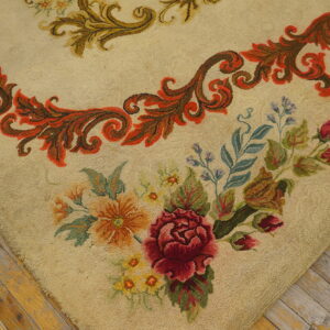 Beige low-pile rug featuring red roses and intricate floral and scrolling patterns on worn wood flooring.