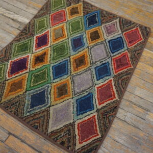 Textured, multicolored rug with nested diamond patterns displayed on distressed wooden floorboards.