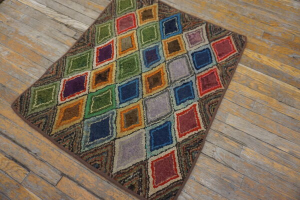 Textured, multicolored rug with nested diamond patterns displayed on distressed wooden floorboards.