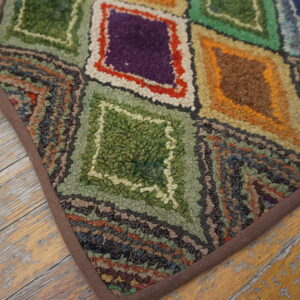 Textured, multicolored rug with geometric diamond shapes sits on distressed light wood flooring.