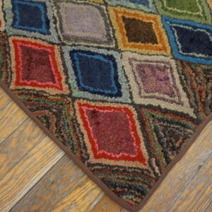 Multicolored hooked rug with diamond patterns and a brown border on distressed wood floors.