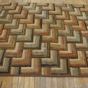 Chunky looped rug with a multi-colored zigzag pattern in earthy tones, resting on rustic wood floors.
