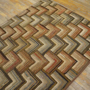 Rustic chevron patterned rug in variegated earth tones, browns, and blues on light wood flooring.