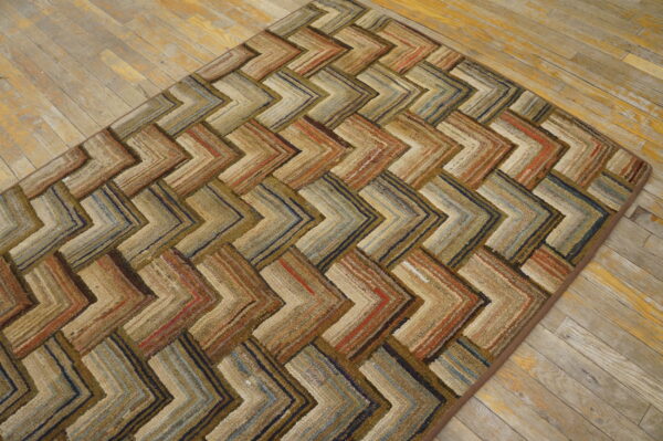 Rustic chevron patterned rug in variegated earth tones, browns, and blues on light wood flooring.