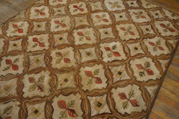 Textured beige rug featuring a brown lattice pattern enclosing red leaves and small geometric designs on wood flooring.