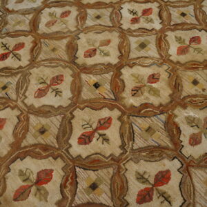 Highly textured beige rug featuring a repeating brown ogee lattice enclosing red and green floral motifs.