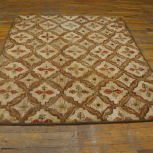 Beige rug with a brown lattice pattern and stylized red and green leaves, displayed on a wooden floor.