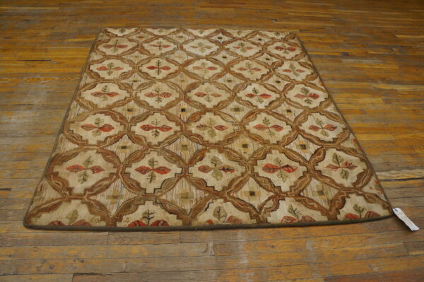 Beige rug with a brown lattice pattern and stylized red and green leaves, displayed on a wooden floor.