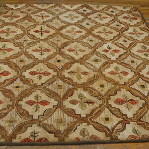 Textured beige rug with brown ogee lattice and colorful leaf accents rests on rustic wood plank flooring.