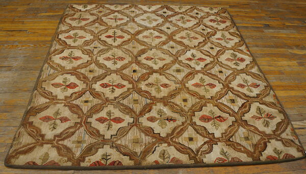 Textured beige rug with brown ogee lattice and colorful leaf accents rests on rustic wood plank flooring.