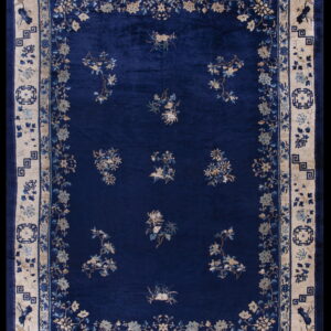 Deep blue high-pile rug with scattered floral patterns and a wide cream-colored geometric border.