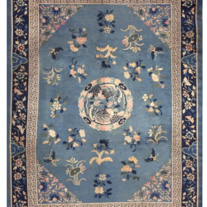 Medium blue rug featuring scattered flowers, a central bird design, and a navy border with a Greek key band.