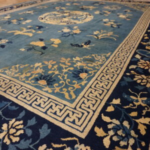 Teal and navy blue rug with gold floral and geometric patterns visible on wood flooring.