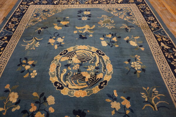 Blue rug with gold and navy florals, featuring a central medallion and detailed geometric borders.