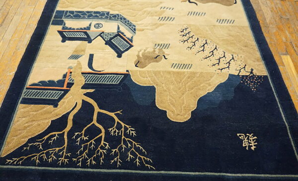 Low-pile rug with a complex beige and dark blue landscape design displayed on worn wooden planks.