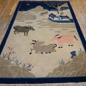 Deep navy bordered rug with a pastoral scene of oxen, hills, and blue buildings on distressed wood plank floors.