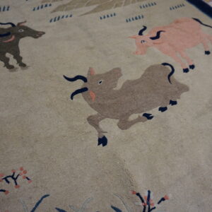 Close-up showing a beige patterned rug with stylized bulls, floral sprigs, and dark blue accents.