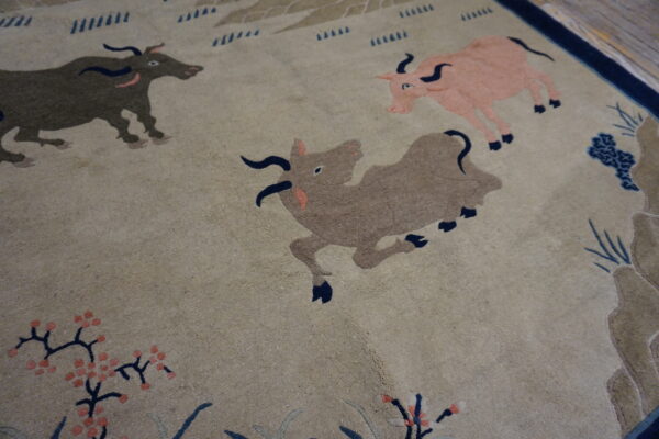 Close-up showing a beige patterned rug with stylized bulls, floral sprigs, and dark blue accents.