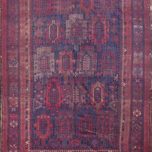 Low-pile rug with geometric patterns in faded indigo blue, deep red, and distressed brown tones.