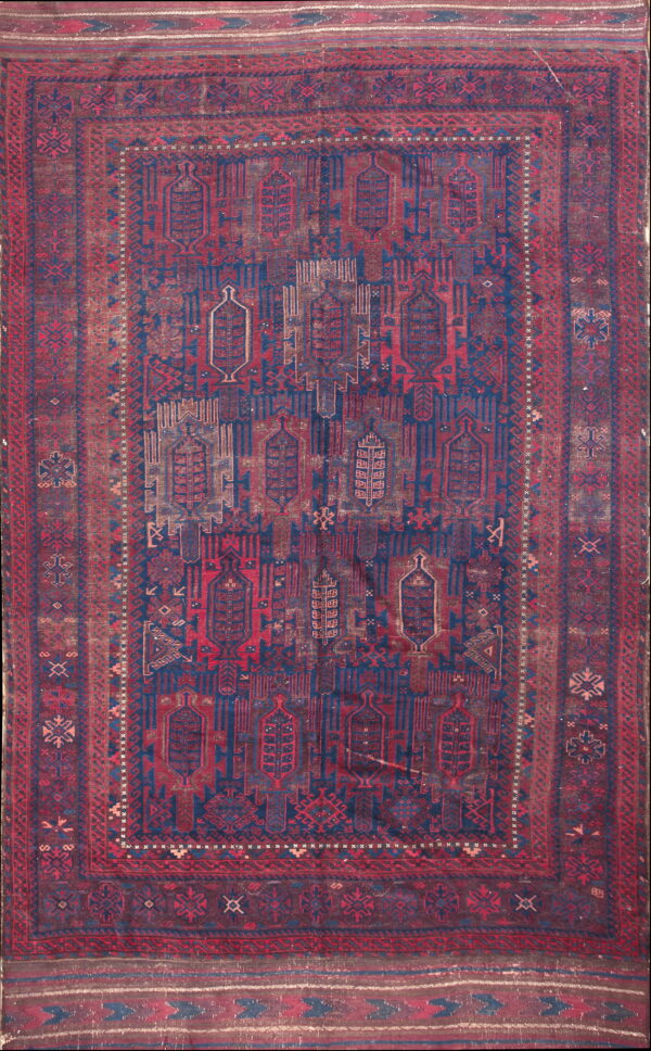 Low-pile rug with geometric patterns in faded indigo blue, deep red, and distressed brown tones.