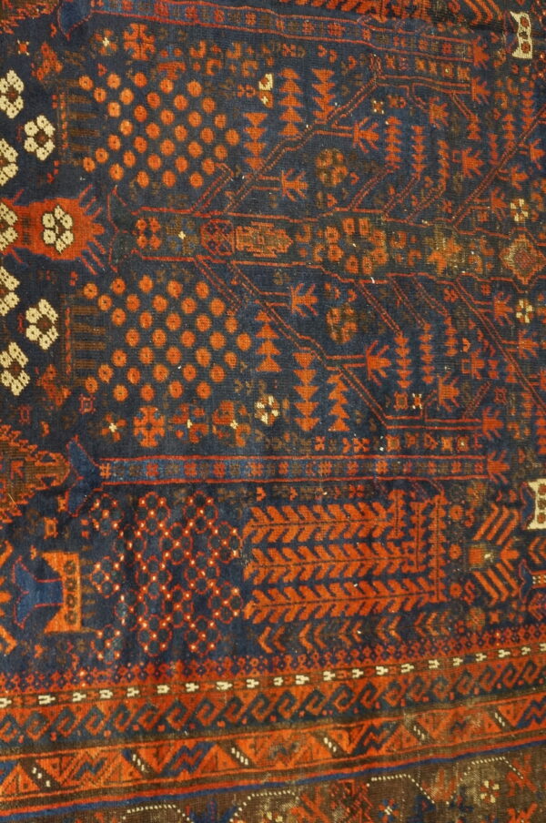 Traditional blue and rust orange rug detail featuring dense geometric motifs and patterned horizontal borders.