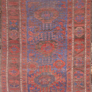 Geometric rug patterned in vibrant blue and red against a mottled dark brown ground.