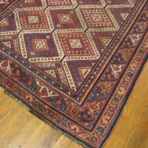 Red, navy, and cream geometric rug with complex borders on distressed wood plank flooring.
