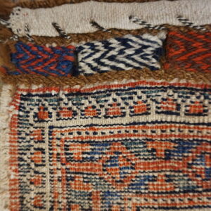 Detailed view of a woven rug border featuring geometric patterns, textured bands, and brown shag accents.