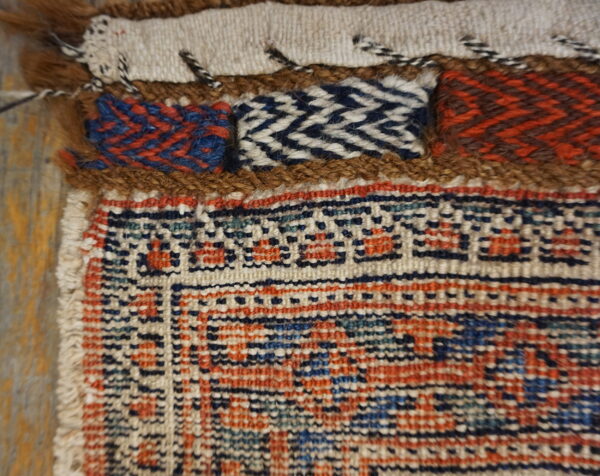 Detailed view of a woven rug border featuring geometric patterns, textured bands, and brown shag accents.