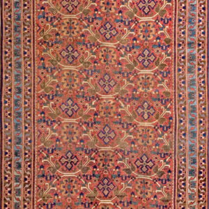 Muted red rug with a repeating geometric and stylized floral pattern in blue, olive, tan, and white.
