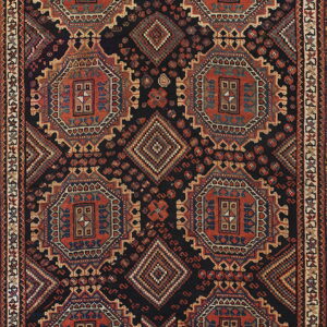 A geometric tribal rug with repeating terracotta and blue octagonal medallions on a dark navy background.