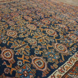Detailed view of a navy blue rug with dense geometric patterns in rust, pink, and light blue.