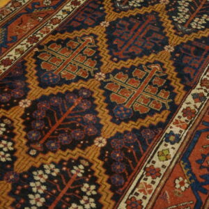 Geometric runner rug featuring stylized trees in navy, rust red, and gold on distressed wooden flooring.