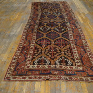 Dark blue and rust tribal runner rug with geometric patterns lies on worn golden wood flooring.