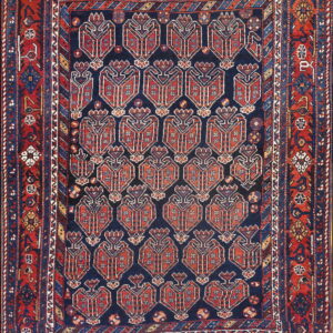 Red and blue tribal rug with a navy center field containing repeating shield-like geometric motifs.