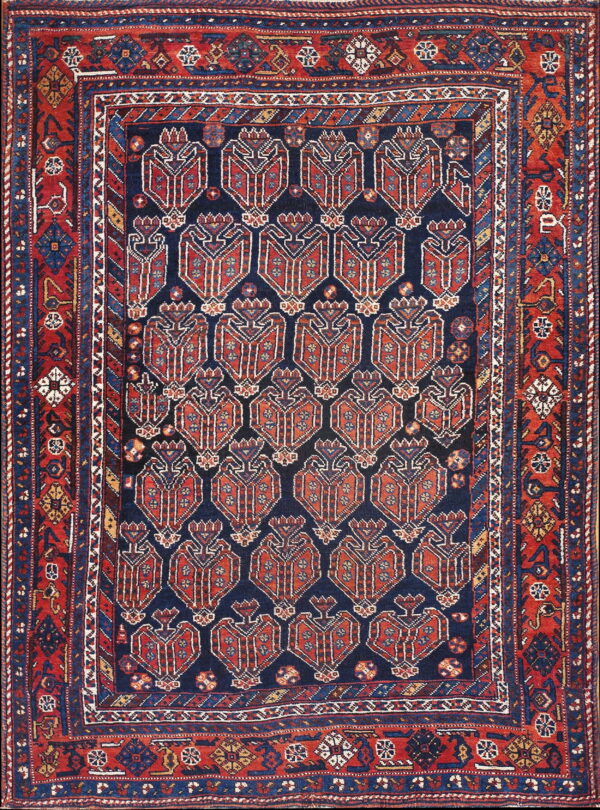 Red and blue tribal rug with a navy center field containing repeating shield-like geometric motifs.