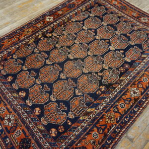 Geometric navy and rust rug with repeating medallion motifs displayed on worn light wood planks.
