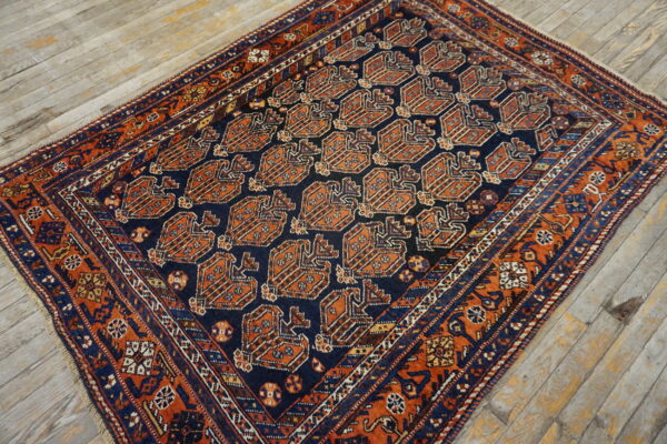 Geometric navy and rust rug with repeating medallion motifs displayed on worn light wood planks.