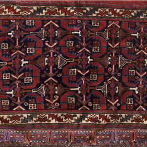 Geometric rug with deep red and navy blue repeating tribal motifs and a multi-banded border.