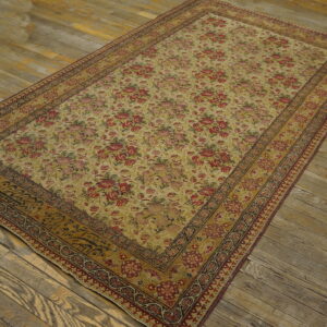 Gold and red floral rug featuring a detailed border, displayed on weathered hardwood flooring.